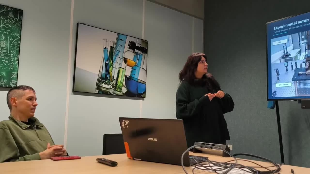 Bozhena Sotnyk presenting her internship work beside a screen showing the optical-tweezers experimental setup